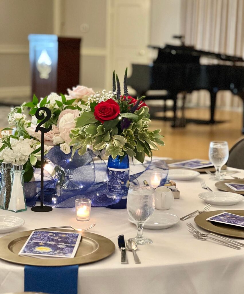 A tablescape at a gala event overlooking a grand piano.