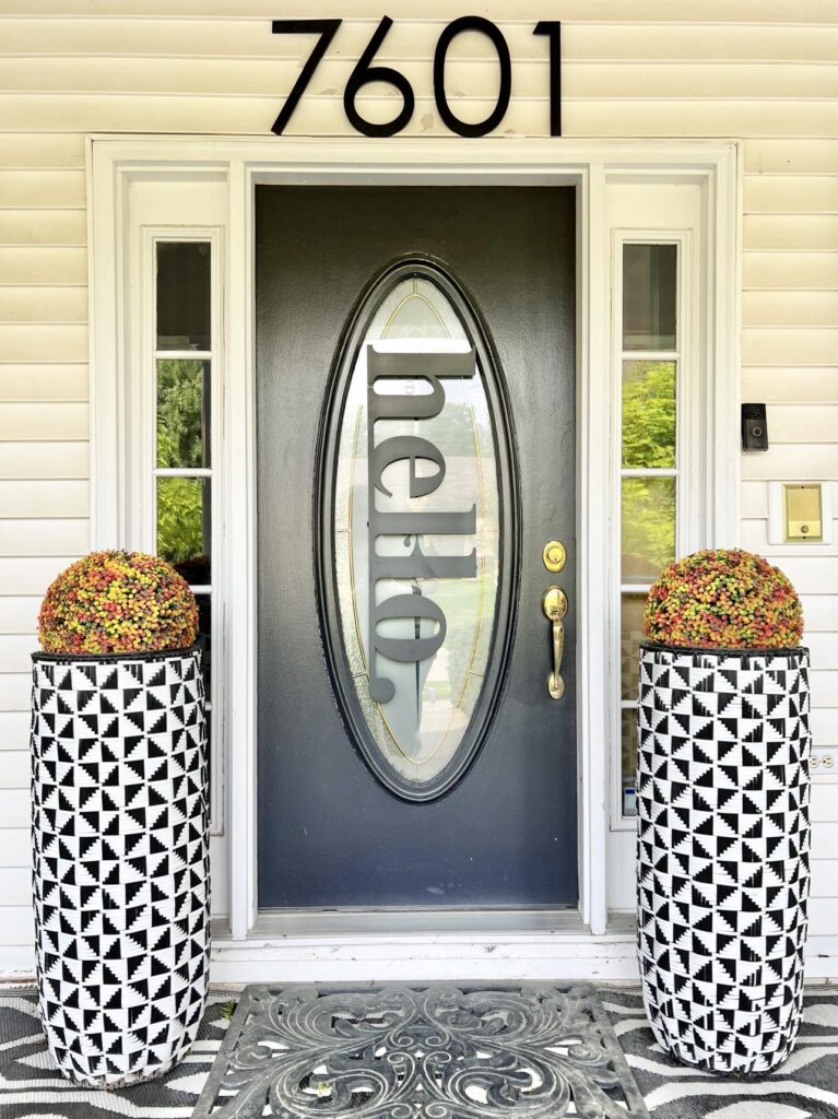 A "hello"sign hanging on the glass insert of a front door.