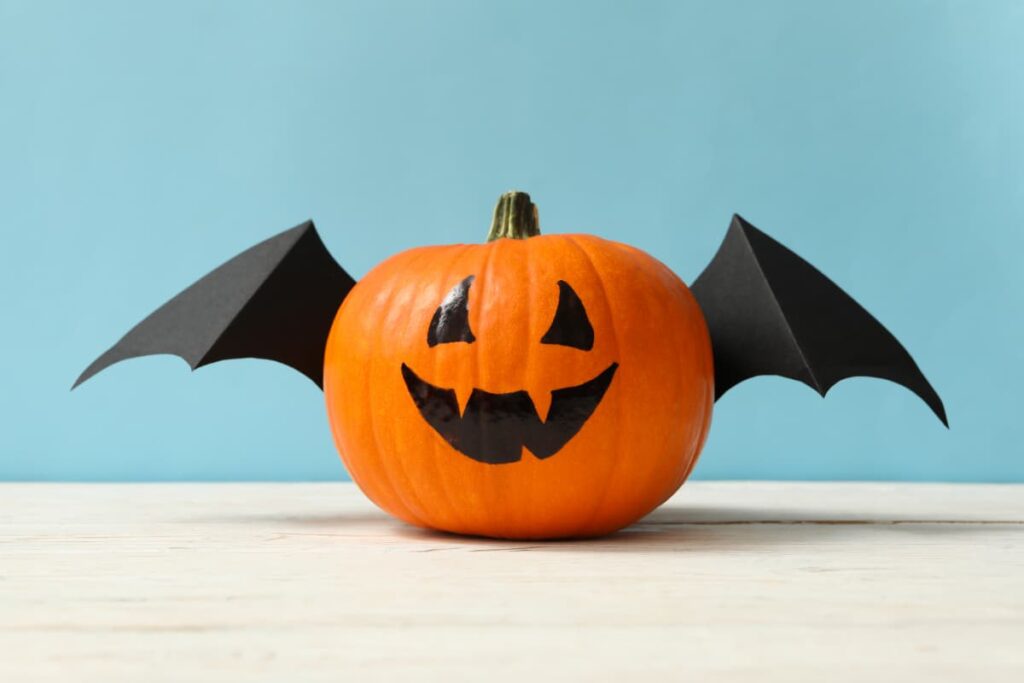 A Halloween pumpkins with paper bat wings.
