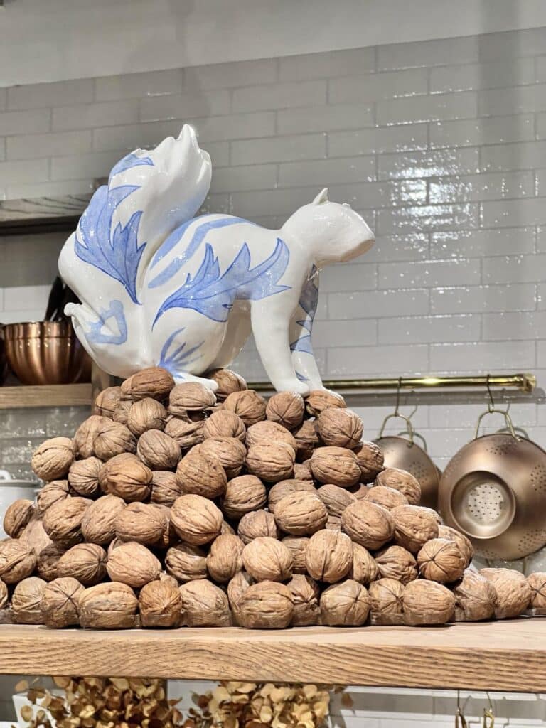 A sculpted chipmunk standing on a pile of walnuts.