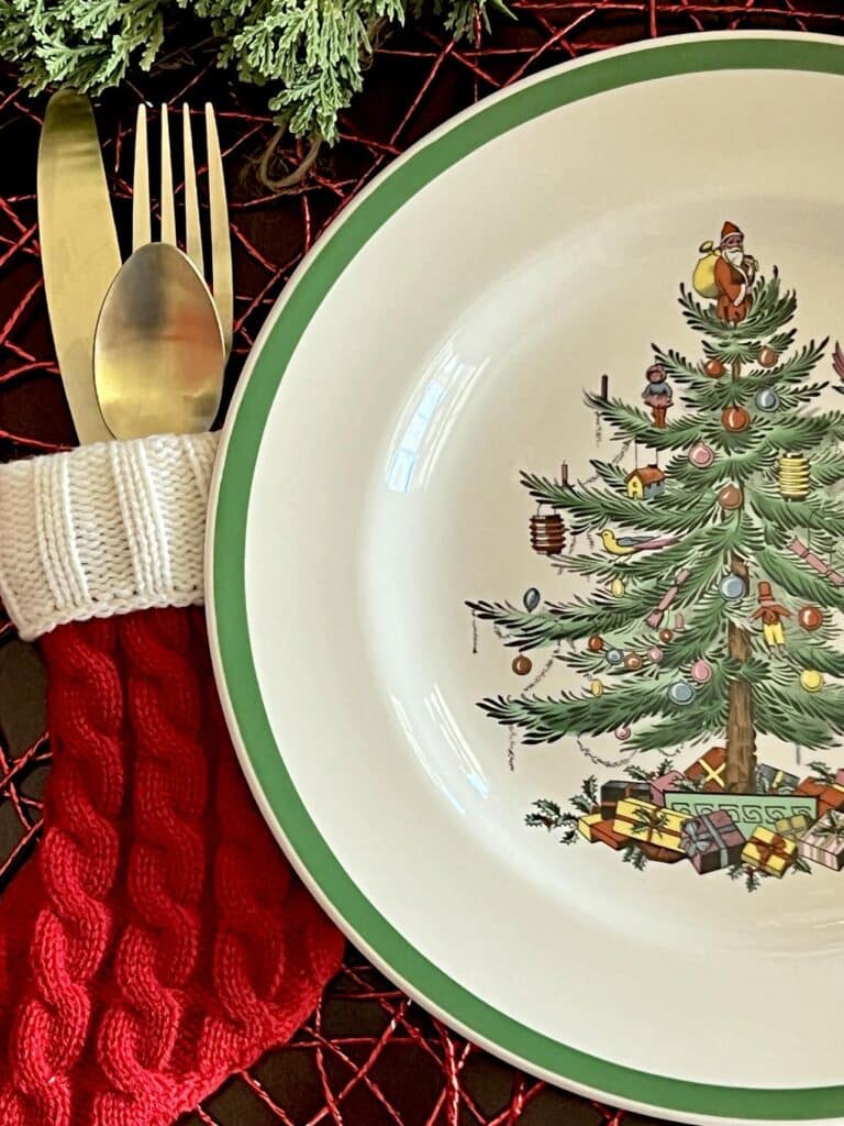 Can you put Spode Christmas tree dishes in the dishwasher? A Spode Christmas tree dinner plate in a place setting with gold silverware.
