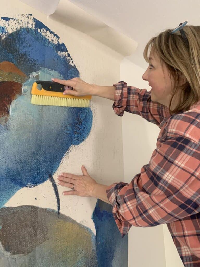 Using a large brush to hang a wallpaper mural.