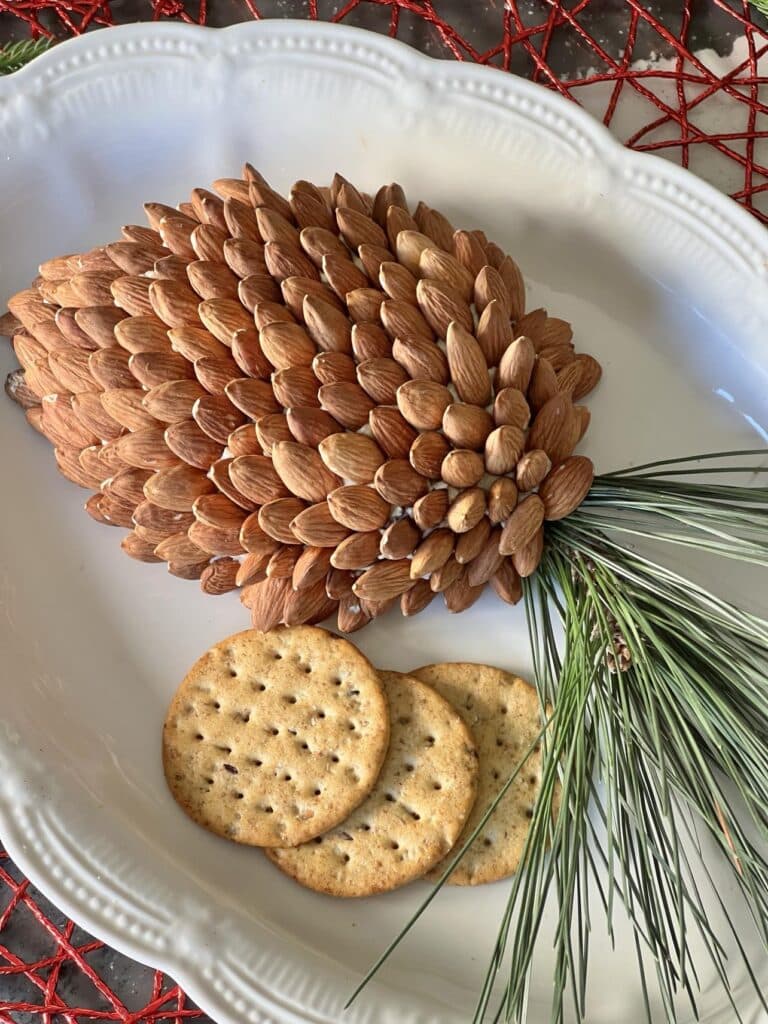 A holiday cheese ball recipe on a serving platter with crackers.
