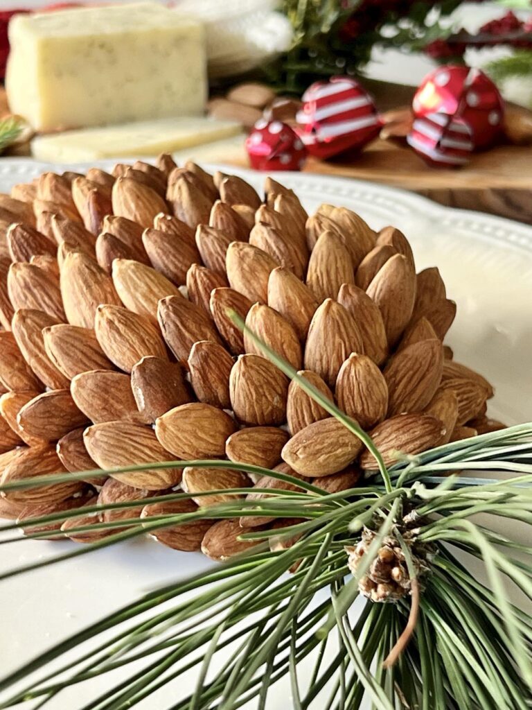 A holiday cheese ball recipe displayed on a tray with a pine bough.