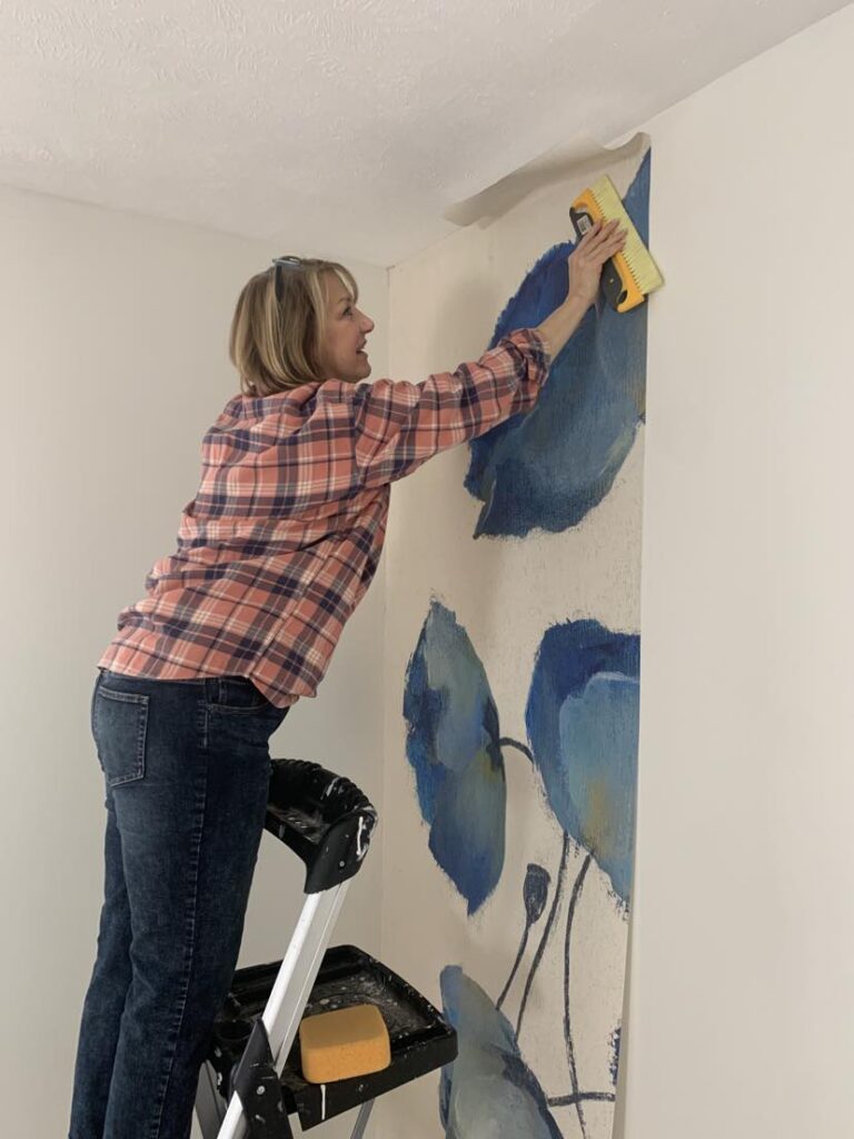 How to hang a wallpaper mural - Using a large brush to smooth out the panels of a wallpaper mural.