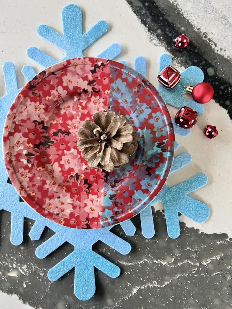A pine cone sitting on a red and blue plate as part of a holiday table setting.
