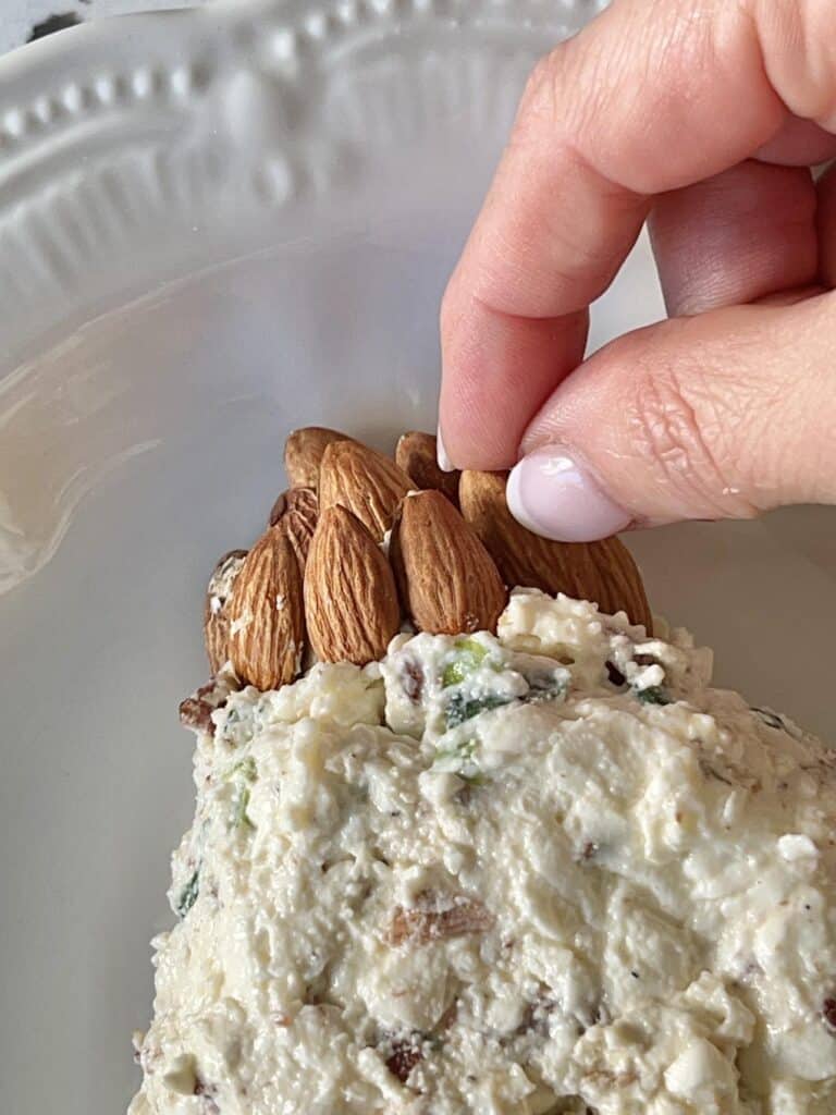 Placing whole almonds into the cream cheese mixture.