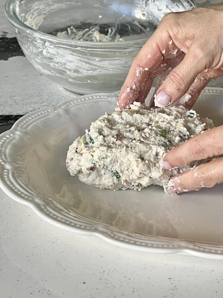 Shaping the holiday cheese ball recipe mixture into the shape of a pine cone.