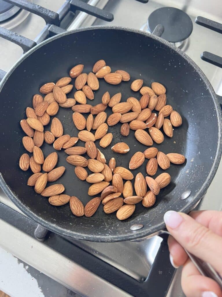 A pan of almonds toasting on the stovetop.
