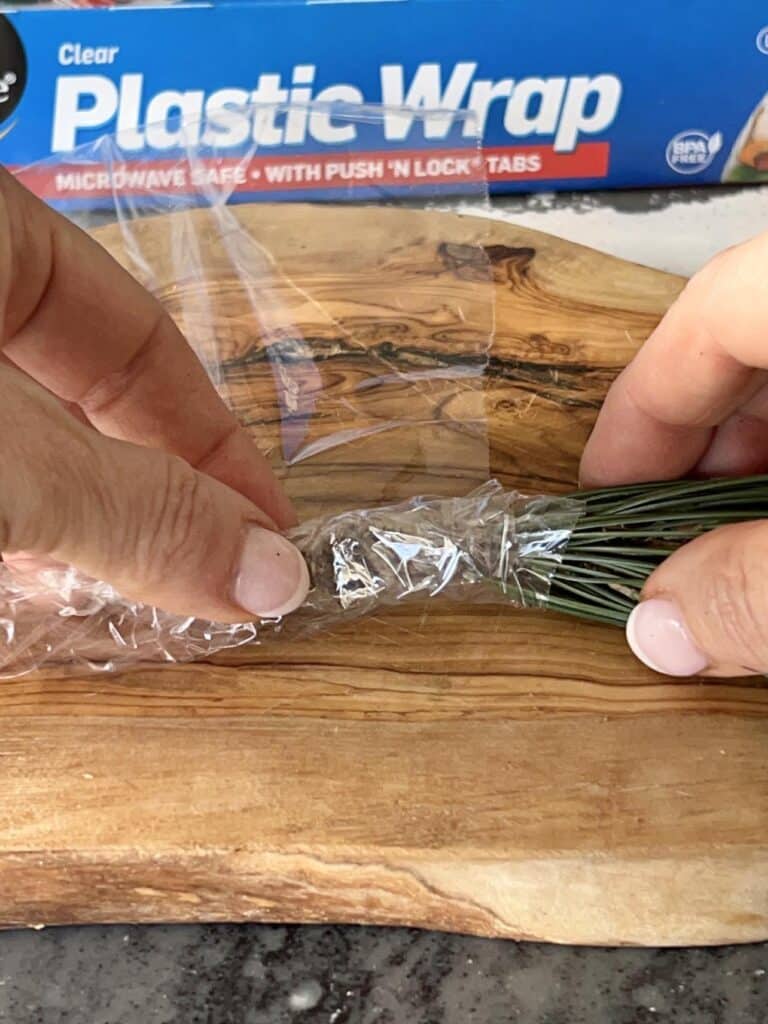 Wrapping a pine bough with plastic wrap.