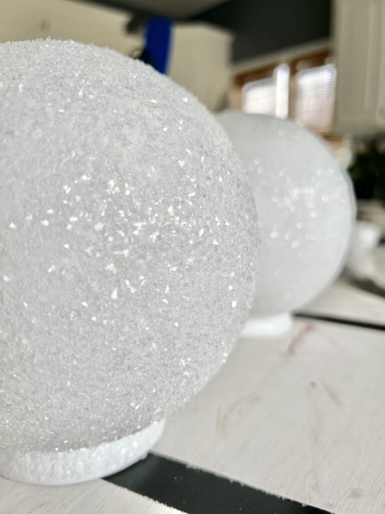 diy faux snowballs lined up and dryingg on the countertop.