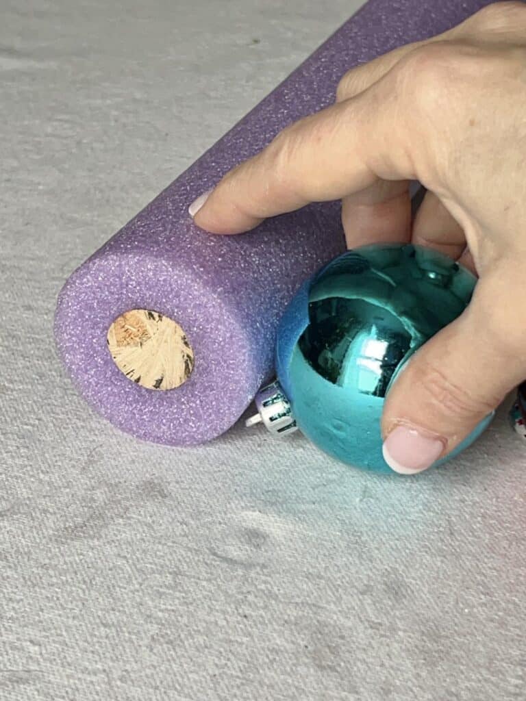 Gluing an ornament to the side of a pool noodle Christmas ball ornaments ideas.