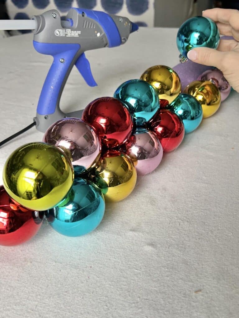 Stacking Christmas ball ornaments on top of a pool noodle for holiday swag and centerpiece ideas.