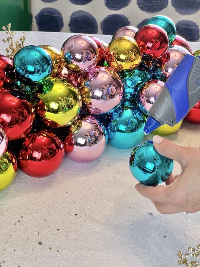 Hot gluing ornaments to a Christmas centerpiece.