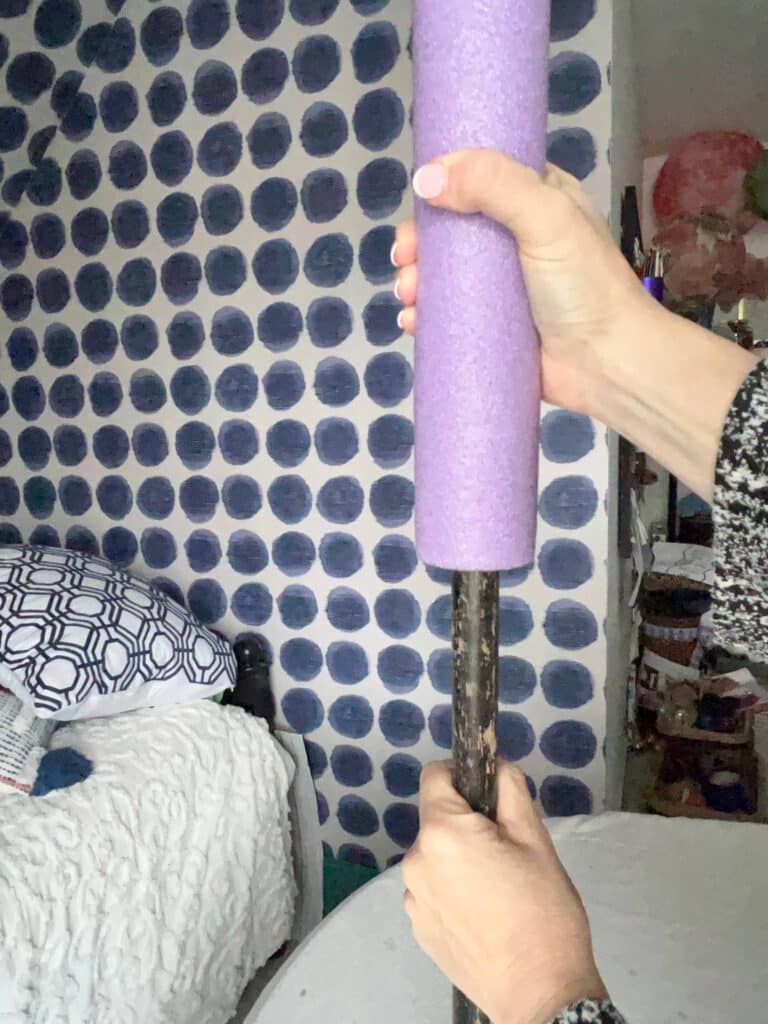 Pushing a pool noodle onto a cut broomstick.