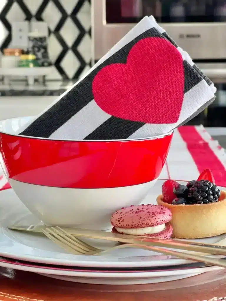 A red and white bowl with aa striped heart napkin.