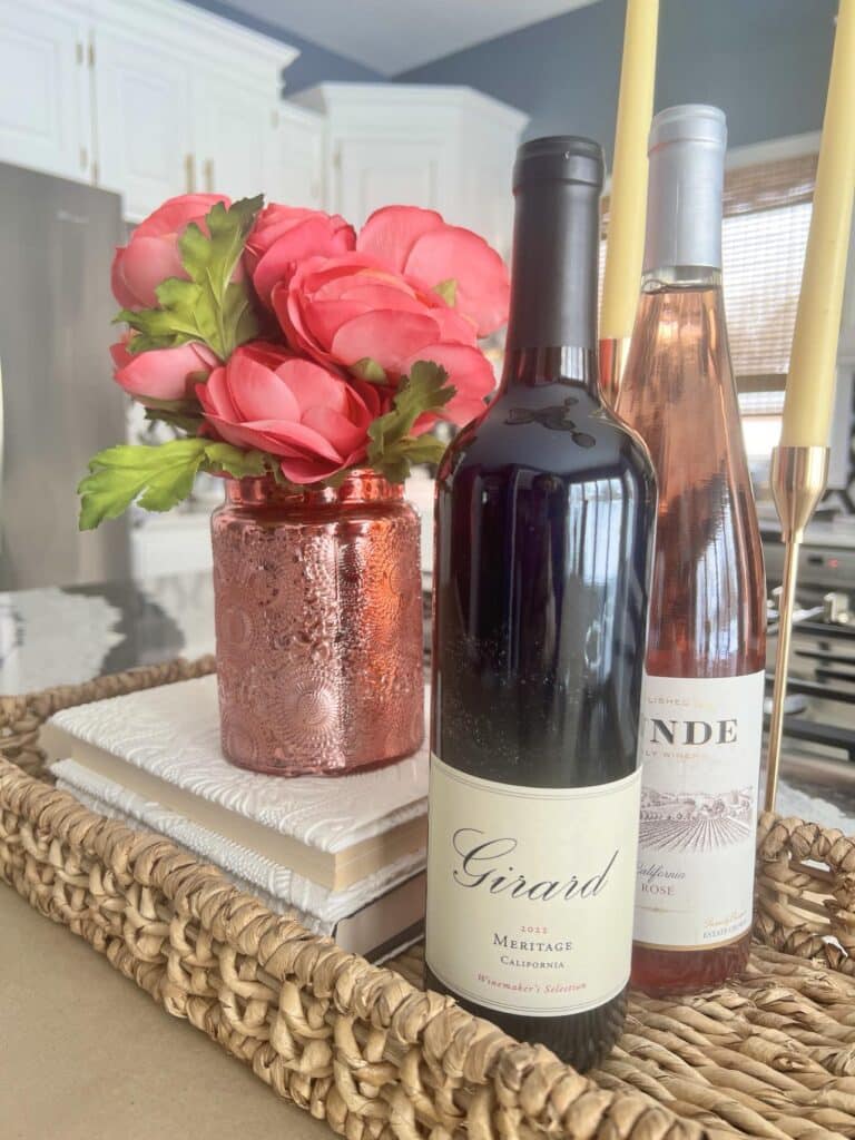 Wine bottles and flowers displayed in a basket on a kitchen island for how to decorate in the kitchen.