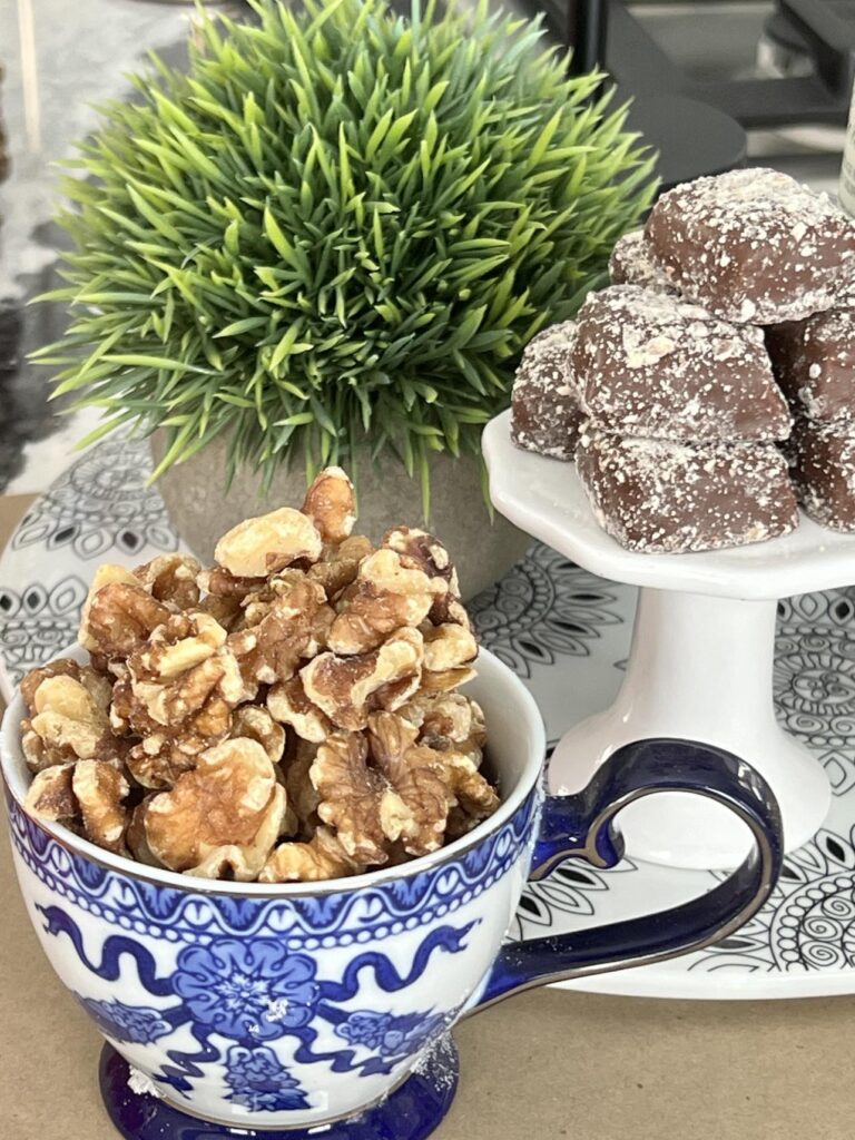 A teacup full of walnuts and a stack of almond toffee.