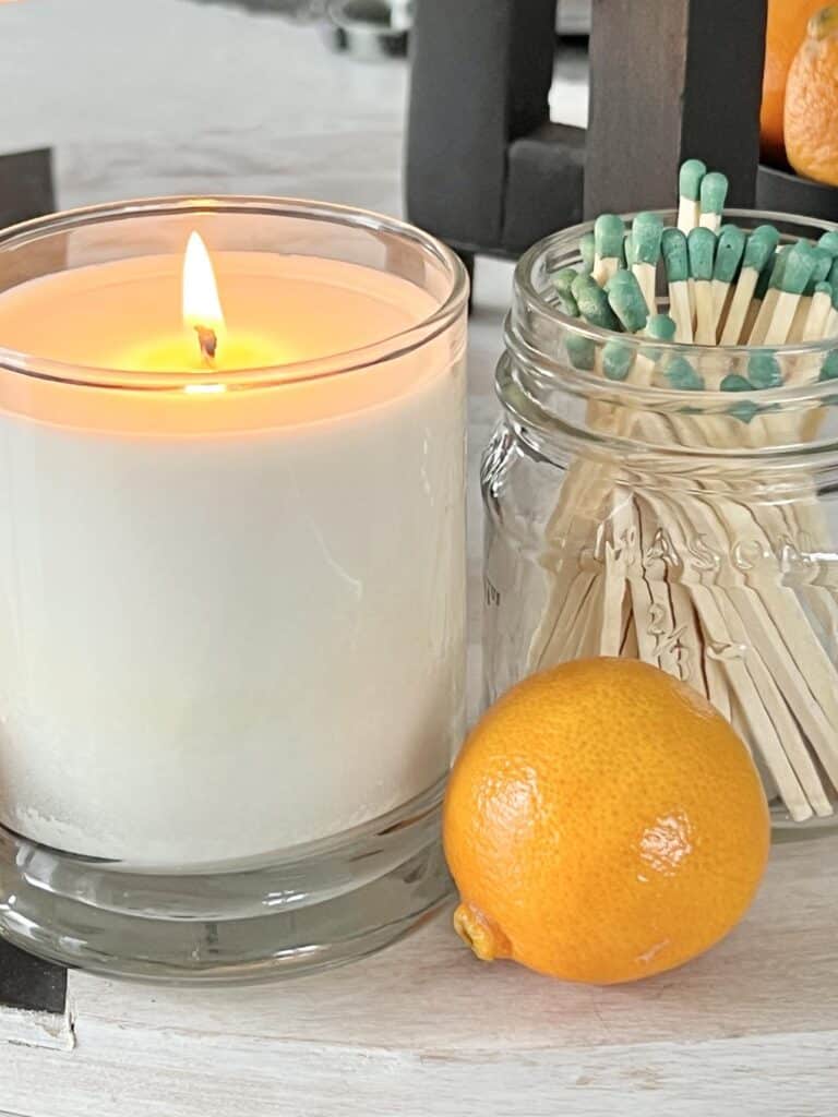 A lighted jar candle sitting sitting beside a DIY match striker jar.