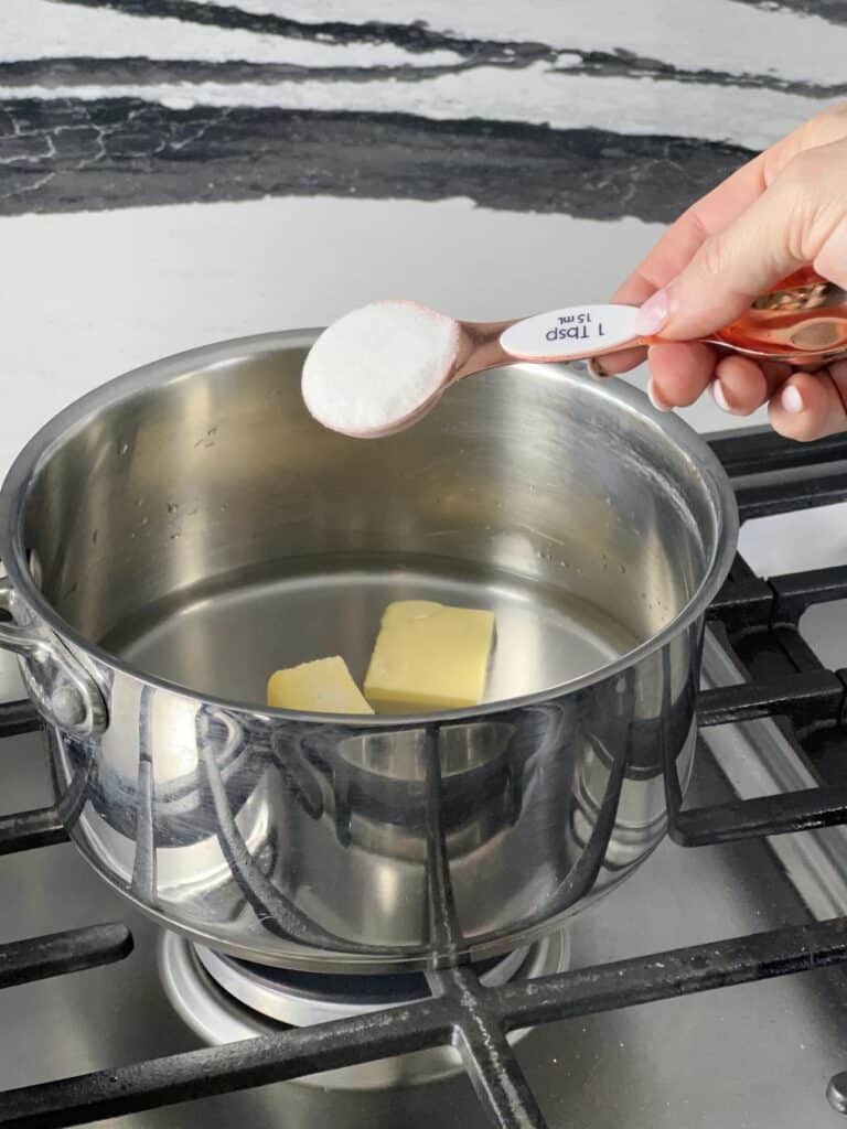Pouring sugar into pot with water and butter.