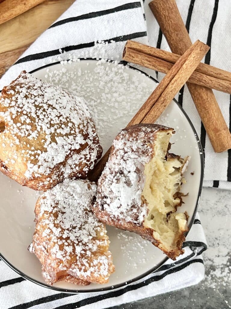 Three apple beignets with one half eaten.