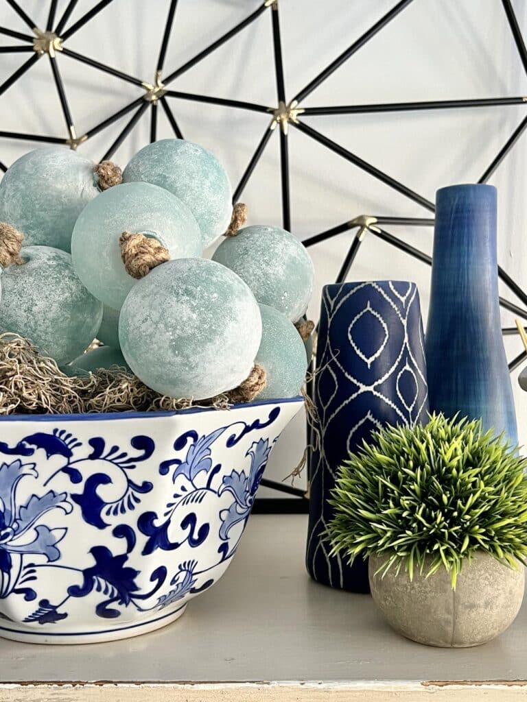 Large glass bead garland sitting in a blue and white chinoiserie bowl to decorate the top of a dresser.