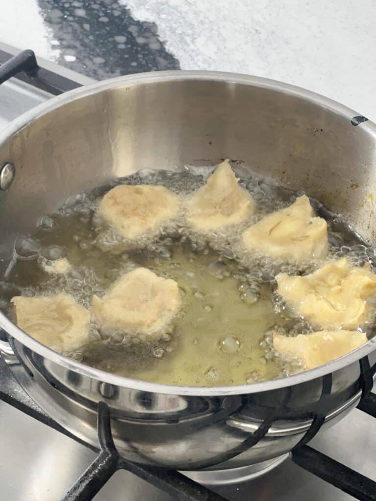 Apple beignet dough frying in oil.