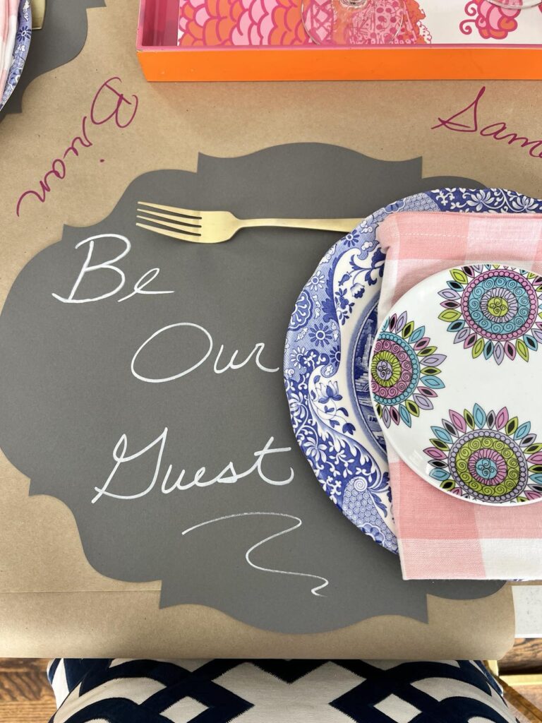 DIY valentine table decorations that include a paper placemat with the phrase "Be Our Guest" written on it.