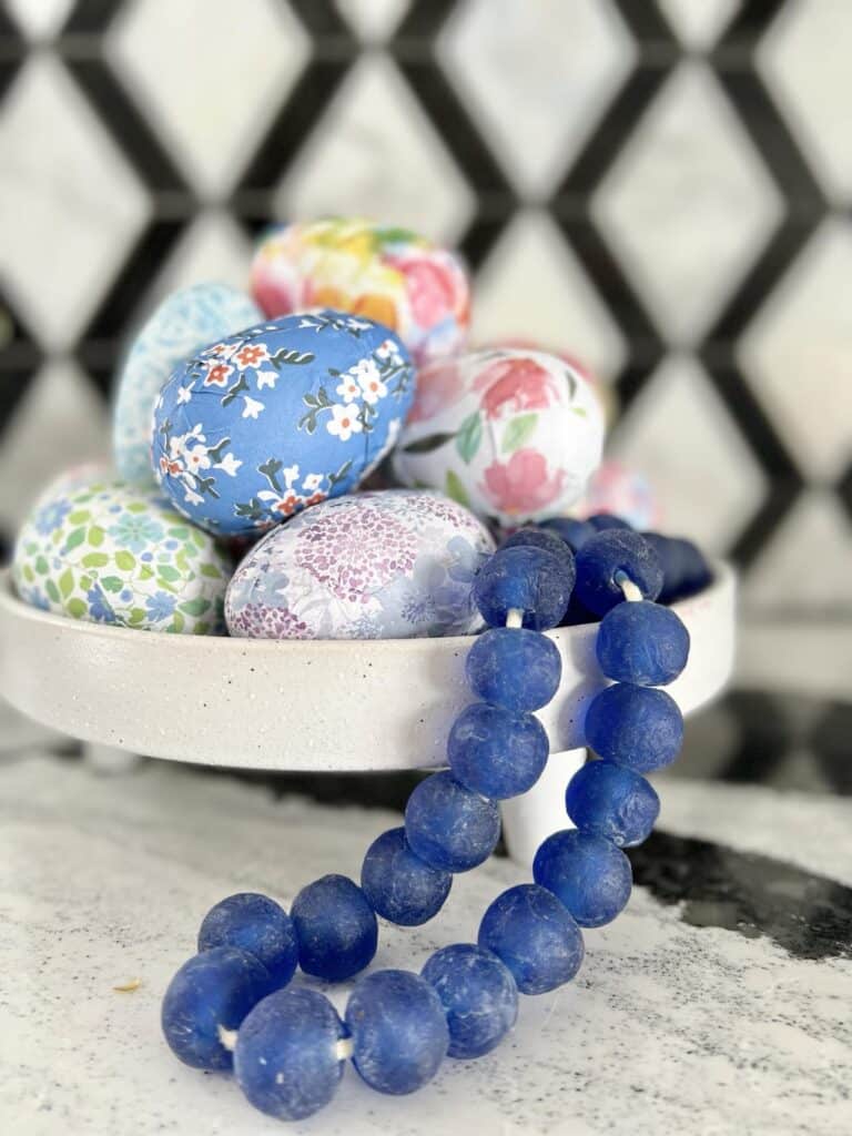 Blue glass bead garland used to decorate aa bowl with patterned Easter eggs.