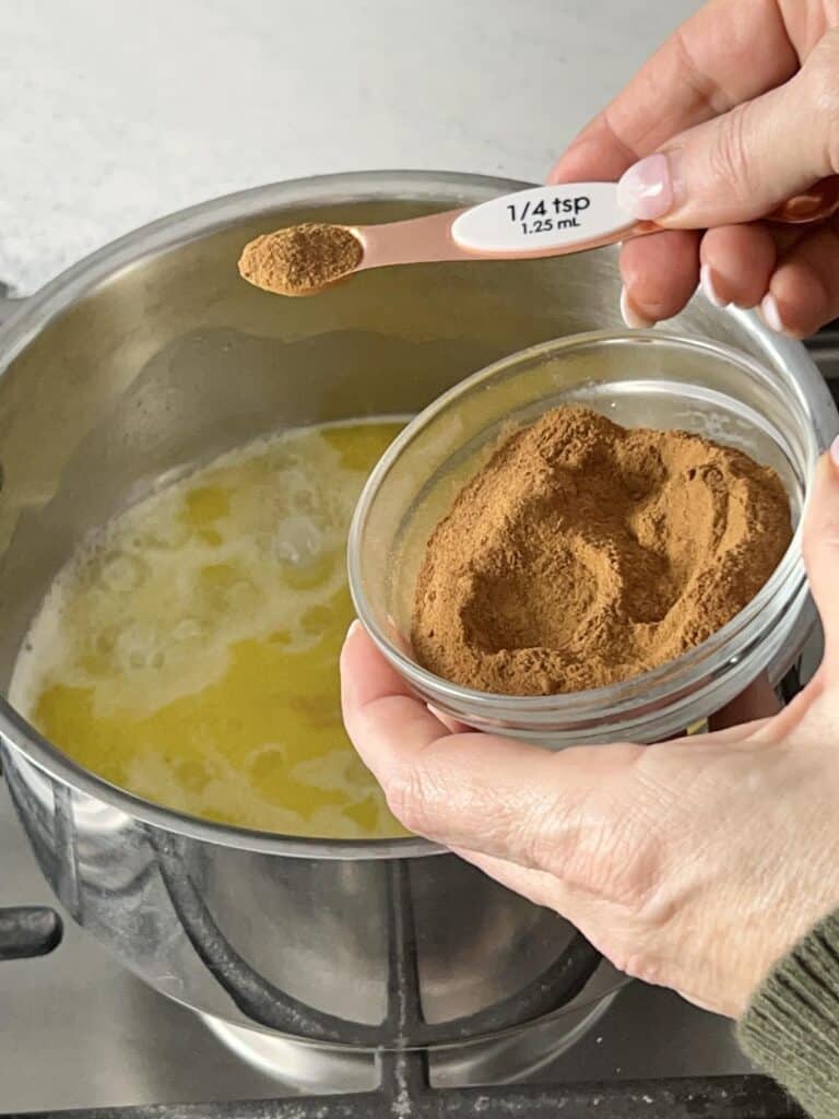 Adding cinnamon to the apple beignet batter mixture.