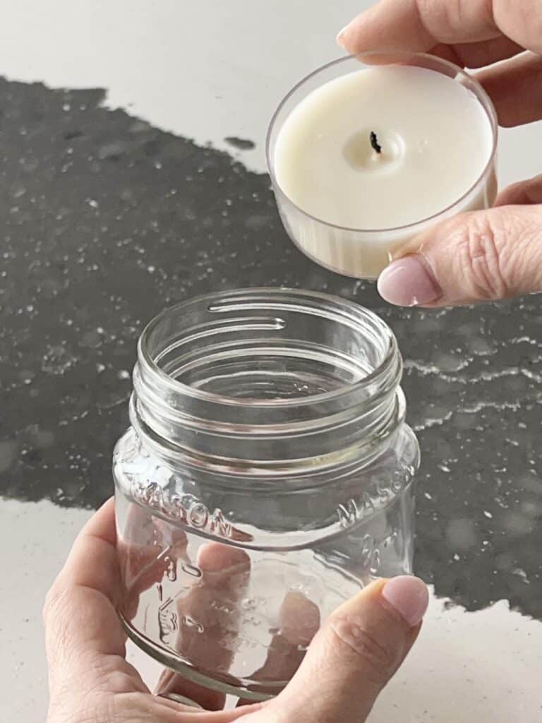 Placing a tea light into an empty clean candle jar.