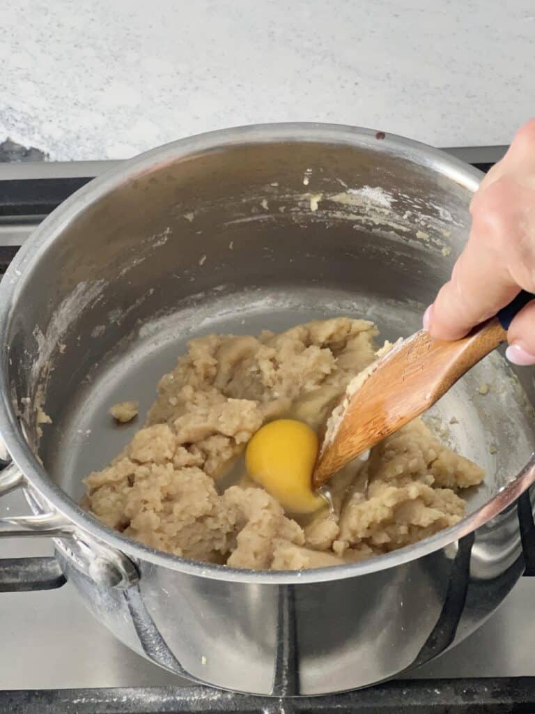 Adding an egg to the apple beignet mixture.