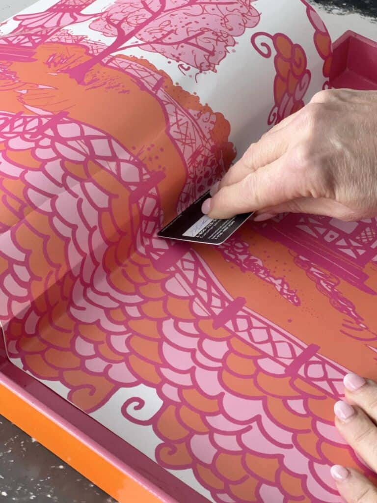 Pressing a piece of wallpaper into a tray with the edge of a credit card.