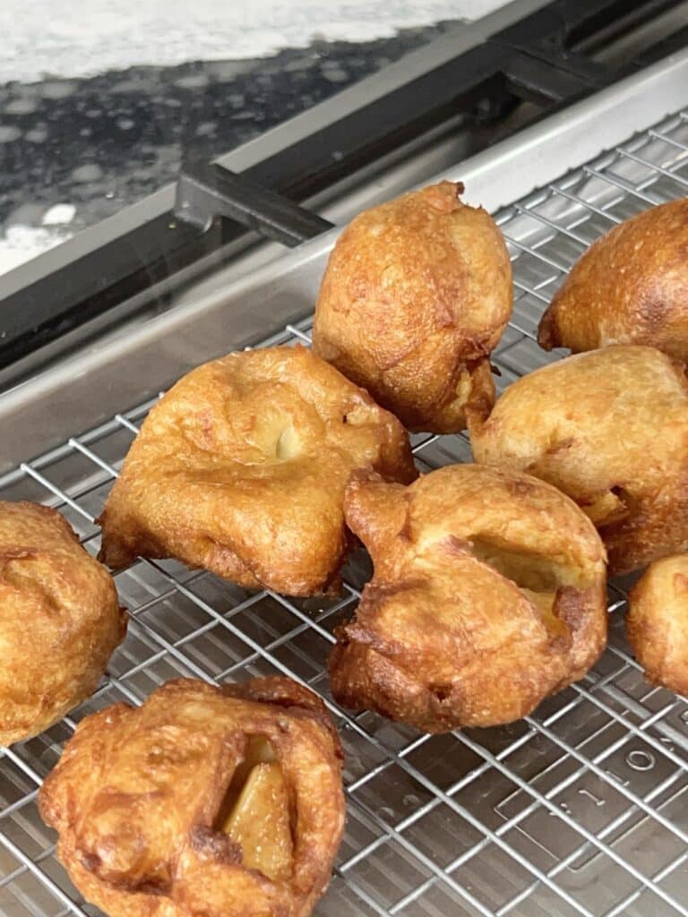 Fried apple beignet on a cooling rack.