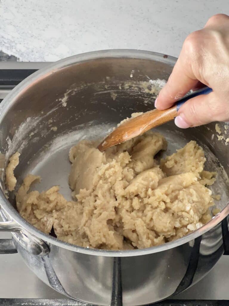 Stirring the apple beignet ingredients together in a pan.