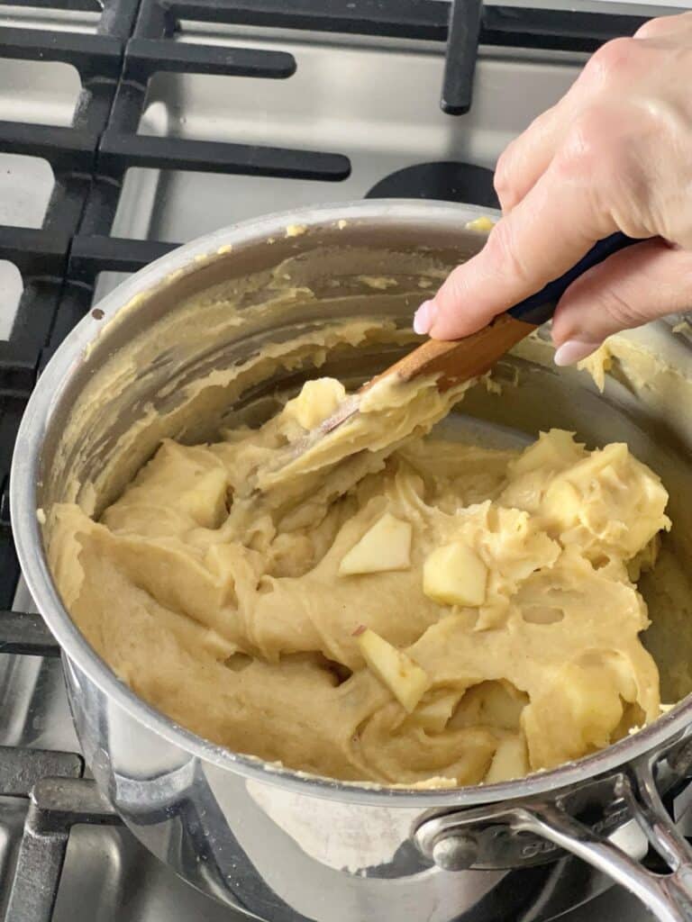 Stirring apples into beignet dough.