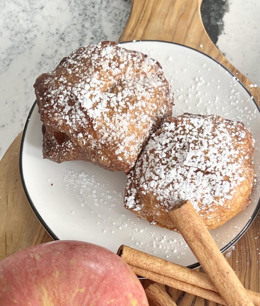 Two apple beignets on a plate.