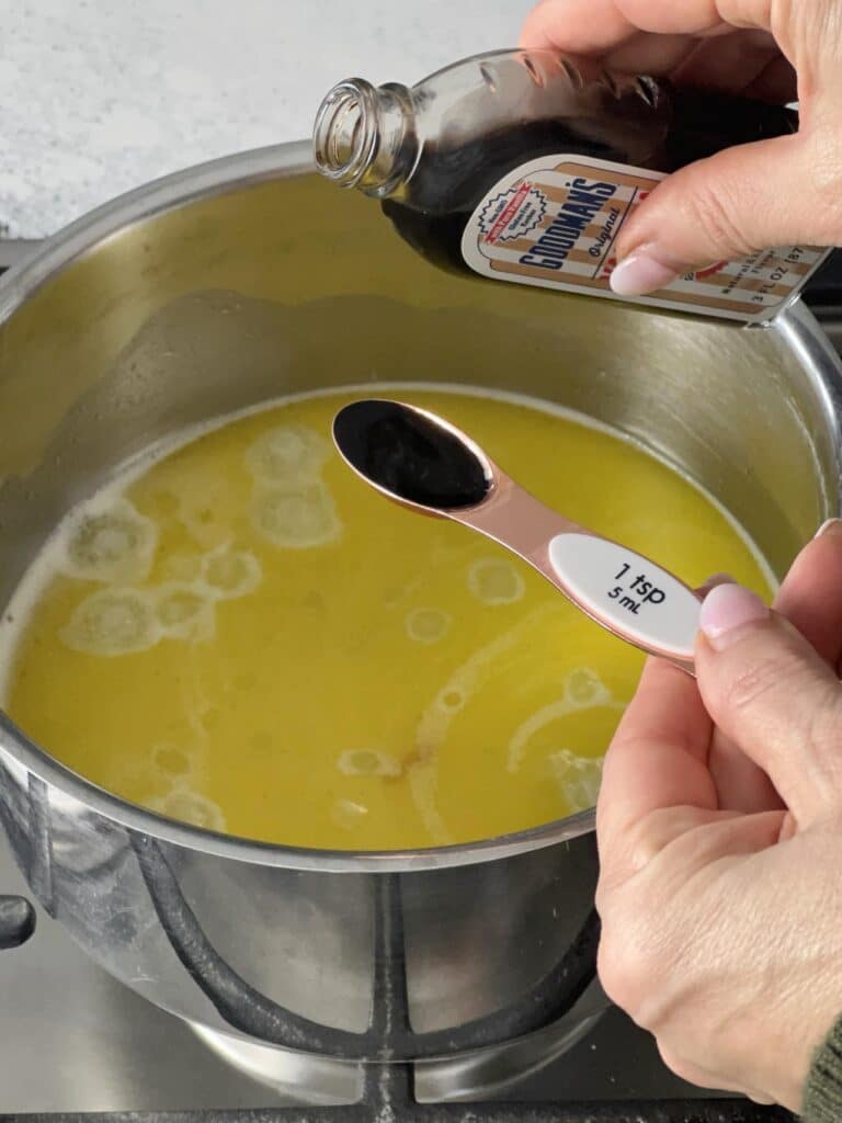 Pouring vanilla into a pan for an apple beignet recipe.