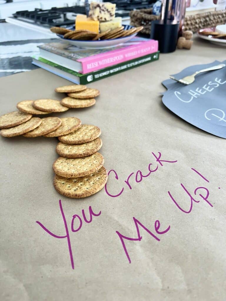 A row of crackers leading to a plate of cheeses.