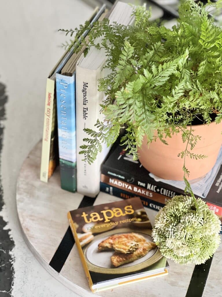 how to decorate a kitchen island - displaying cookbooks and a plant on a wood charcuterie board.