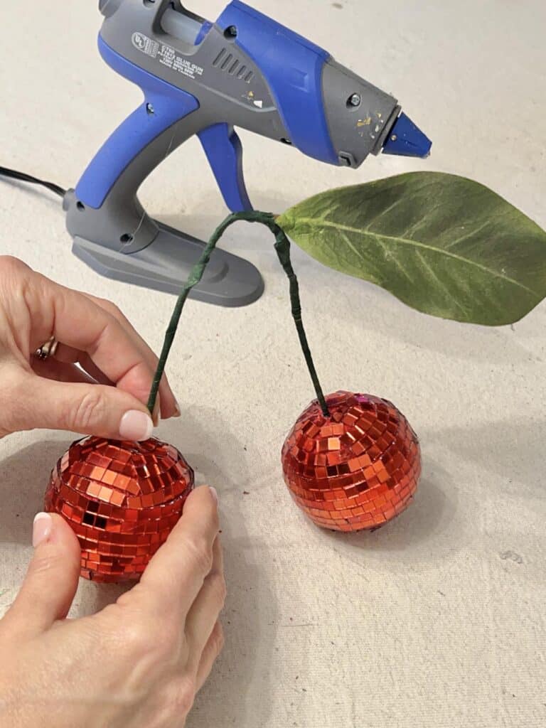 Sticking the wrapped pipe cleaner into the DIY Disco Ball Cherries.