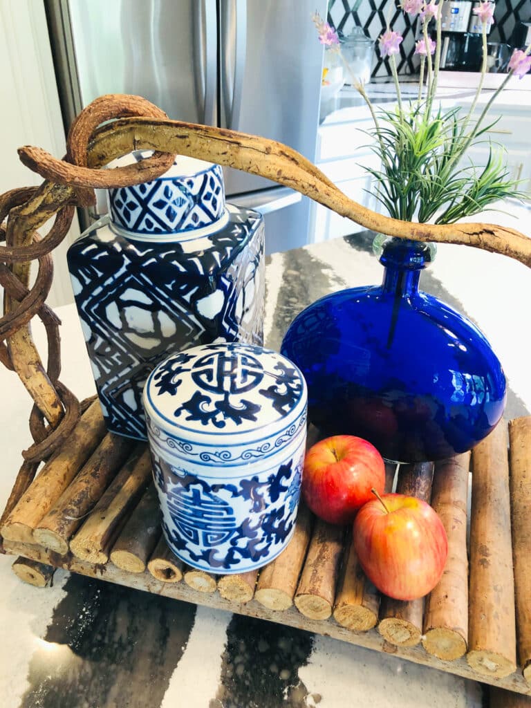 A wooden tray holding blue and white jars on a kitchen countertop.