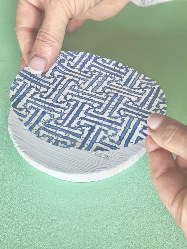 Applying the paper napkin to the top of the DIY decoupage coasters.