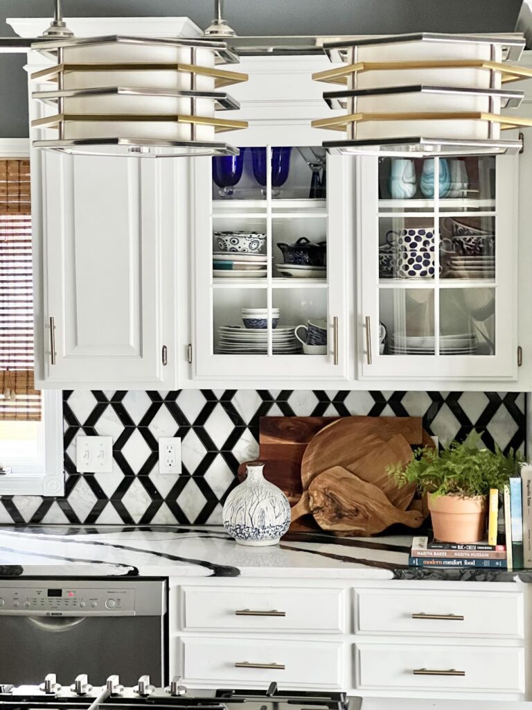 A white kitchen with warm wood cutting boards propped against the tile backsplash.