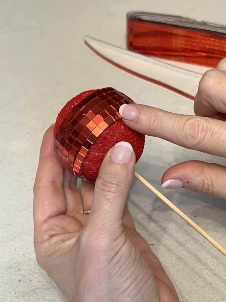 Pressing tiles onto ball for DIY Disco Ball Cherries.