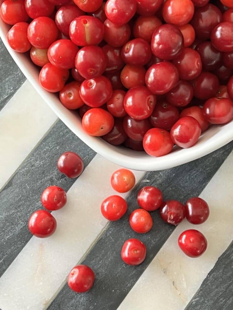 A bowl of red grapes spilling out of a fruit bowl.