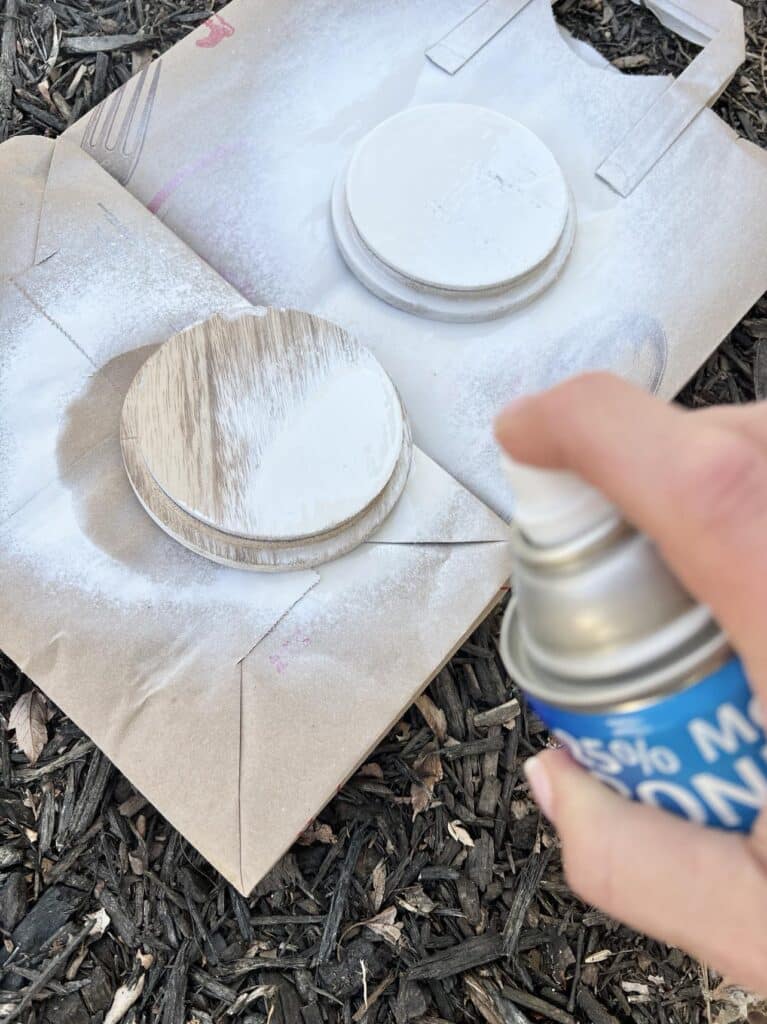 Spray painting wood lids white to prep for DIY decoupage coasters.