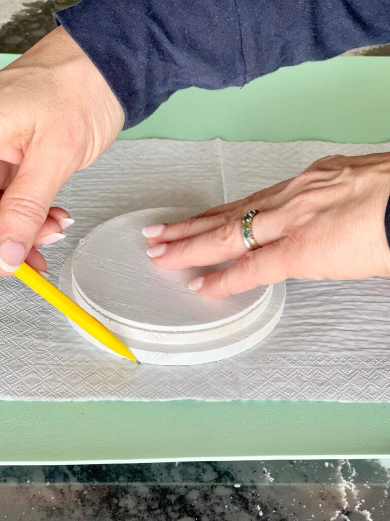 Tracing around a wood candle jar lid to make DIY decoupage coasters,