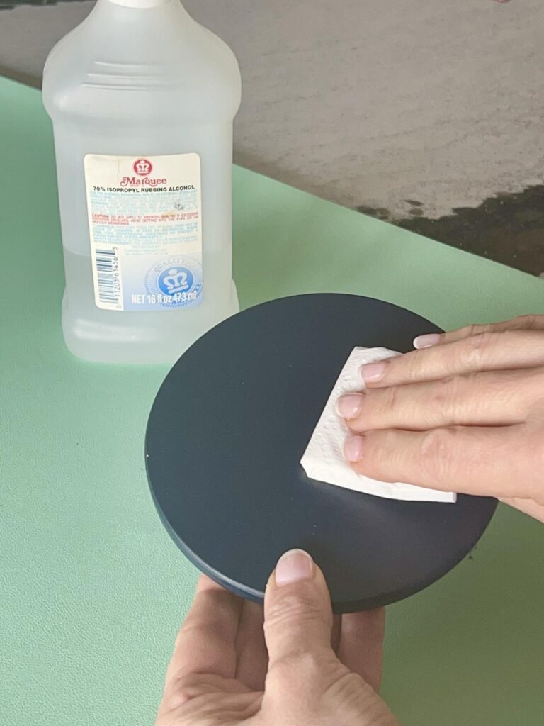 Wiping the top of a painted jar lid with rubbing alcohol.
