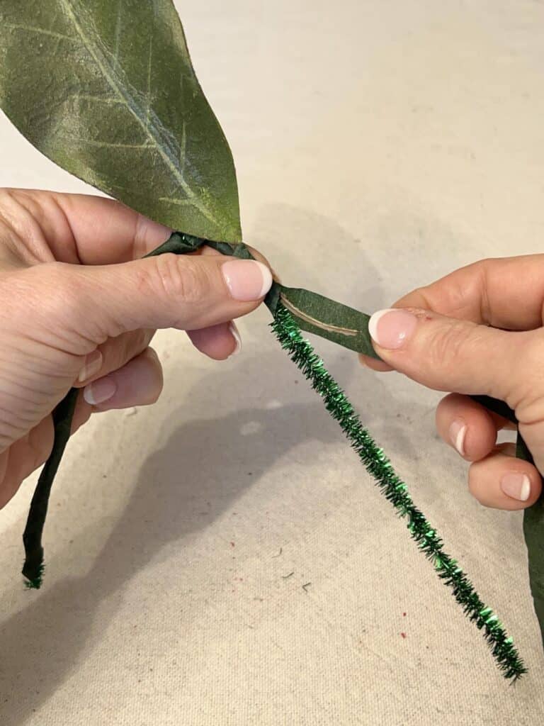 Wrapping a leaf onto a pipe cleaner with floral tape.